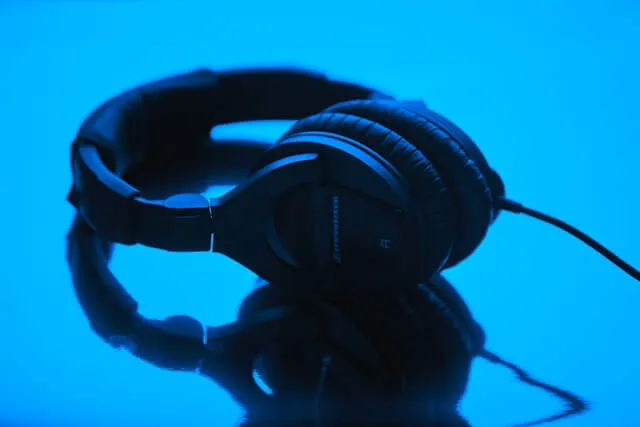 A pair of professional over-ear headphones on a reflective blue surface